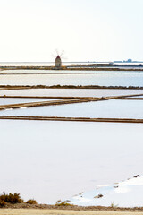 Landscape view of the salt Pans of Trapani in Sicily with colorful waters, white salt piles and red wind mill