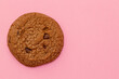 One chocolate chip cookie on pink background