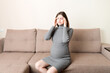 © sosiukin - Young pregnant woman suffering from headache on sofa in home. Maternity healthcare concept