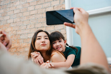 Wall Mural - Mother and daughter taking photo with smartphone together at home.