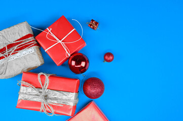 Different gift boxes and christmas balls lie on blue surface. New year festive card