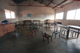 Fototapeta Do akwarium - wide angle horizontal photography of  an African school classroom with white walls, bright windows and many empty wooden and metal chairs, in the Gambia . Africa with natural light