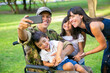 © Mangostar - Joyful happy disabled military man taking selfie with his wife and two kids in park. Family togetherness and support concept