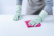 © RomixImage - Woman housekeeper wearing protective gloves and using rag to wipe clean the table surface.