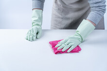 Woman Housekeeper Wearing Protective Gloves And Using Rag To Wipe Clean The Table Surface.