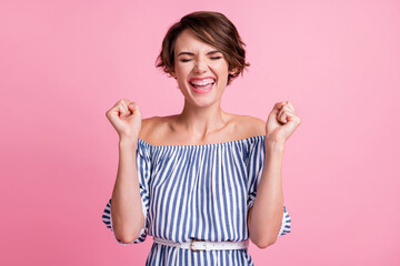 Photo portrait of happy woman celebrating with fists up isolated on pastel pink colored background