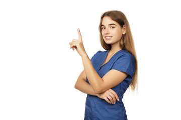 Young beautiful female doctor in a blue surgical gown shows a finger to the side isolated on a white background. Copspace