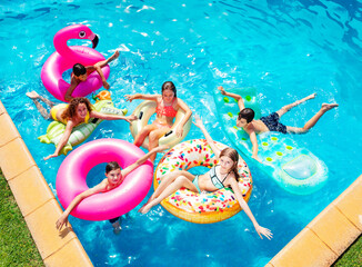 Group of many happy kids friends swim on inflatable ring toys view from above