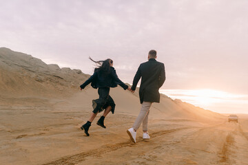 Drone view of a couple in love on the sand dunes at sunset