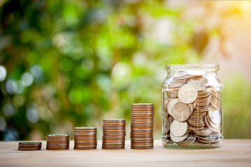 Wall Mural - Stacking of coins and full money in a glass jar for growing growth saving concept investment mortgage fund finance and interest, education, child, future on bokeh background.