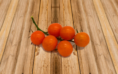 A branch of orange tomatoes on a Board surface