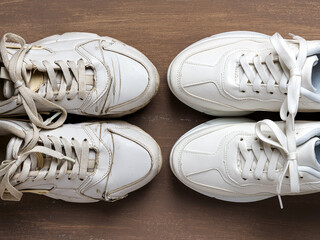 Pair of old dirty white sneakers in front of new clean one on a brown background. Past and future, old and new concepts. Comfortable shoes for active lifestyle, fitness and sports.