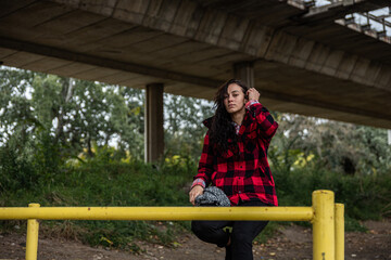 Wall Mural - Young depressed homeless girl or woman sitting alone under the bridge on the street on the cold weather feeling anxious abandoned and freezing 