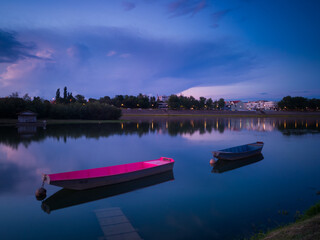 The landscape of the Sava River in summer, moored boats along the shore and a large ominous cumulonimbus cloud above the horizon at dusk