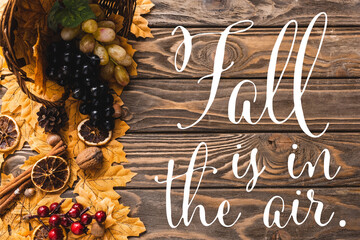 Wall Mural - Top view of autumnal harvest scattered from basket on foliage near fall is in the air lettering on wooden background