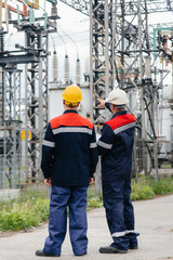 Two specialist electrical substation engineers inspect modern high-voltage equipment. Energy. Industry