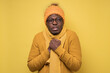 © Viktor Koldunov - Funny african american mature man in yellow scarf and hat freezing in warm clothing. Studio shoot on yellow wall.