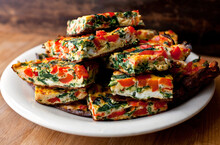 Close Up Of Spinach And Red Pepper Frittata Slices Served On Plate