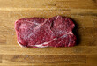 © Andrew Scrivani - Close up of raw meat steak seasoned with kosher salt on wooden table
