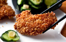 Close Up Of Pork Katsu With Pickled Cucumbers And Shiso Served On Plate