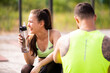 © Georgii - Young couple in stylish sportswear resting with bottle of water after family workout