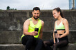 © Georgii - Athletic young couple using mobile phone apps after workout in urban sitting on stairs
