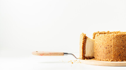 Wall Mural - Homemade classic New York cheesecake cut on the wooden board. Vanilla pie with cheese and crunchy crust on the whiite background. Close up, macro shot