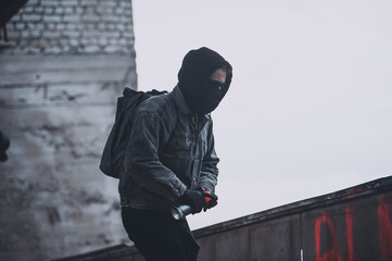 Punk styled man hided his face with black mask, hood and glasses