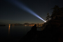 A Person Shining A Bright Flashlight Into The Night Sky Over The Ocean