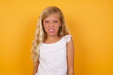 Mad Crazy Beautiful Caucasian Young Girl Standing Against Yellow Background Clenches Teeth Angrily, Being Annoyed With Coming Noise. Negative Feeling Concept.