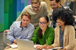 © Friends Stock - Group of happy multiracial business people sitting at desk in the modern coworking space, looking at laptop screen and smiling, working together