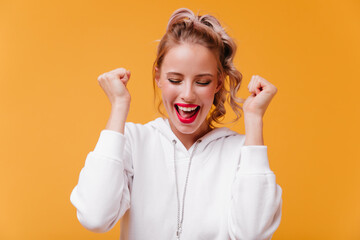 Wall Mural - Attractive girl rejoices victory in competitions. Athlete with bright appearance happily poses for portrait on orange background