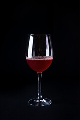 Wall Mural - Vertical shot of a glass of red wine on a black background