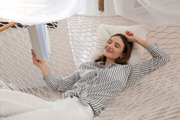 Wall Mural - Happy woman with book in hammock at home