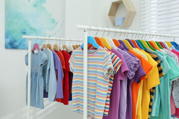 Wall Mural - Different child's clothes hanging on racks indoors