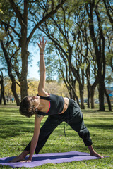 Canvas Print - Vertical shot of a young Caucasian female doing yoga practice in the park