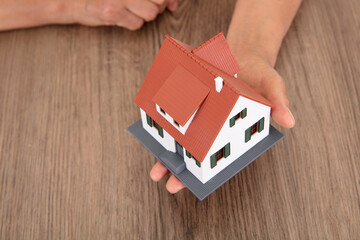 Yellow-skinned old man holding up a small house model with one hand