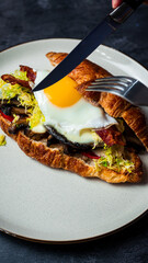 Wall Mural - Cutting Portobello Croissant Breakfast Sandwich with sunny up egg