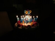 Birthday Cake With Happy Birthday Candles Lit Up In The Dark, Ready To Be Blown Out 