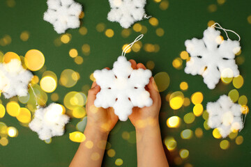 Wall Mural - Kids hands holding decorative snowflake on natural green background. Sale, Holiday, greering card Happy new year, Merry Christmas, banner for your site, invitation, flyer, holiday card