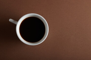 Coffee cup on brown background. Cup of black coffee. Top view with copy space.