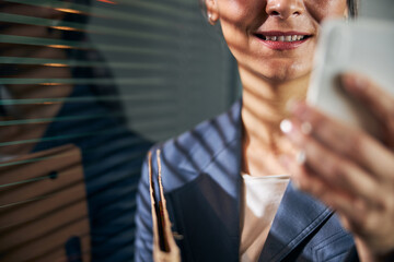 Wall Mural - Joyful woman using mobile phone at work