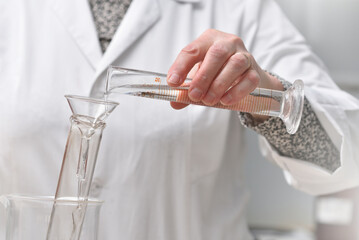 laboratory assistant pours liquid into a test tube close-up