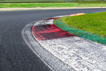 Wall Mural - Close up of rough curb at right turn on motor sport track with green field and black asphalt