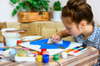 © soleg - a girl drawing blue gouache cardboard, artistic creation at home, makes creative artwork