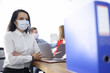 © Тихон Купревич - Employees in protective medical masks are sitting in office at their desk. Safe communication with colleagues during coronavirus pandemic concept