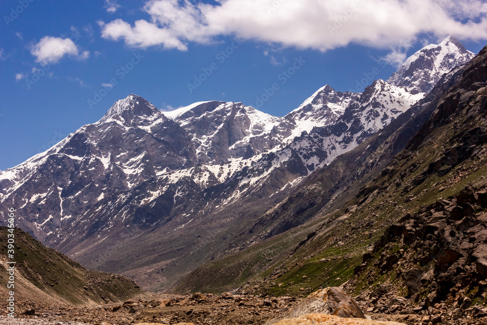 A beautiful landscape of snow capped Himalayan mountains in a green valley in Himachal Pradesh, India.