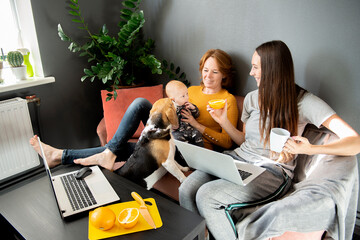 happy family - grandmother, daughter, newborn baby and dog rest in the living room on the couch