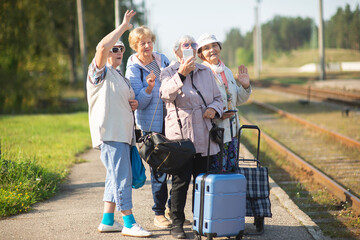 Wall Mural - Group of senior women take a self-portrait on a platform waiting for a train to travel during a COVID-19 pand