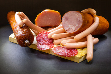 Wall Mural - Different ham and salami with herbs on a dark background